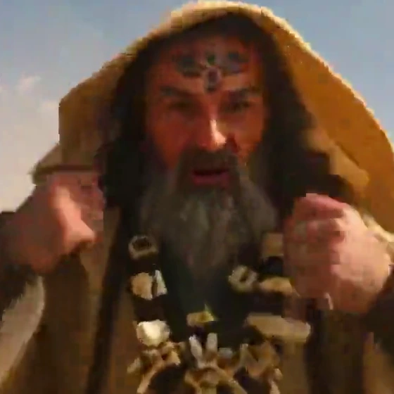 The same crop after two re-encodes at 600 kbit/s: the beard, forehead mark and knuckles have turned into smeared blocks