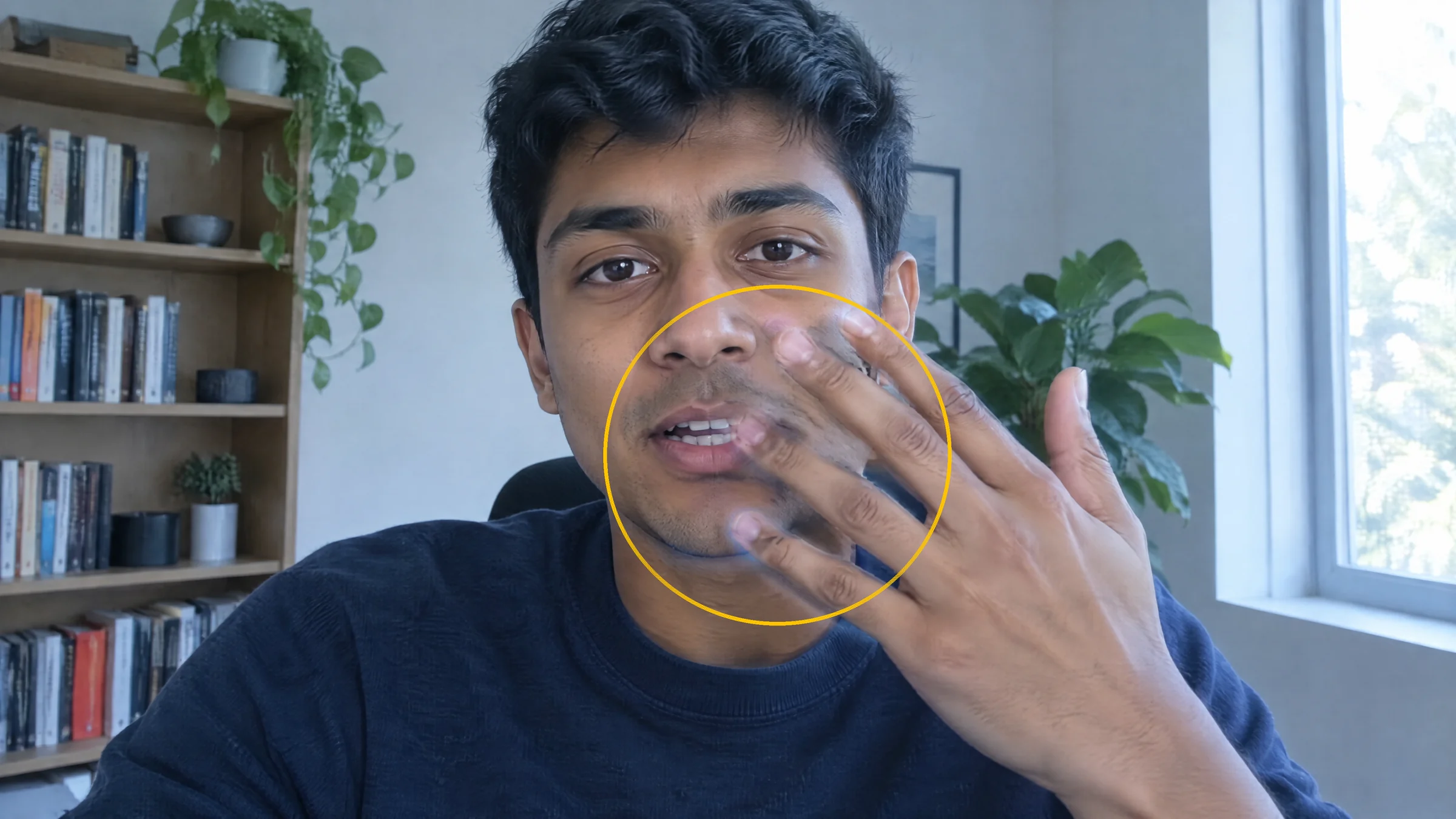 Illustration: an invented young man raises his hand in front of his face on a video call, with a yellow circle around fingers that look ghosted where they cross his cheek and mouth