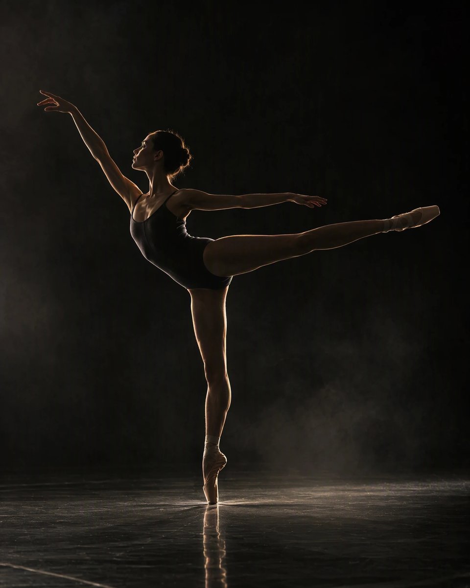 A dancer frozen mid-arabesque in a black studio