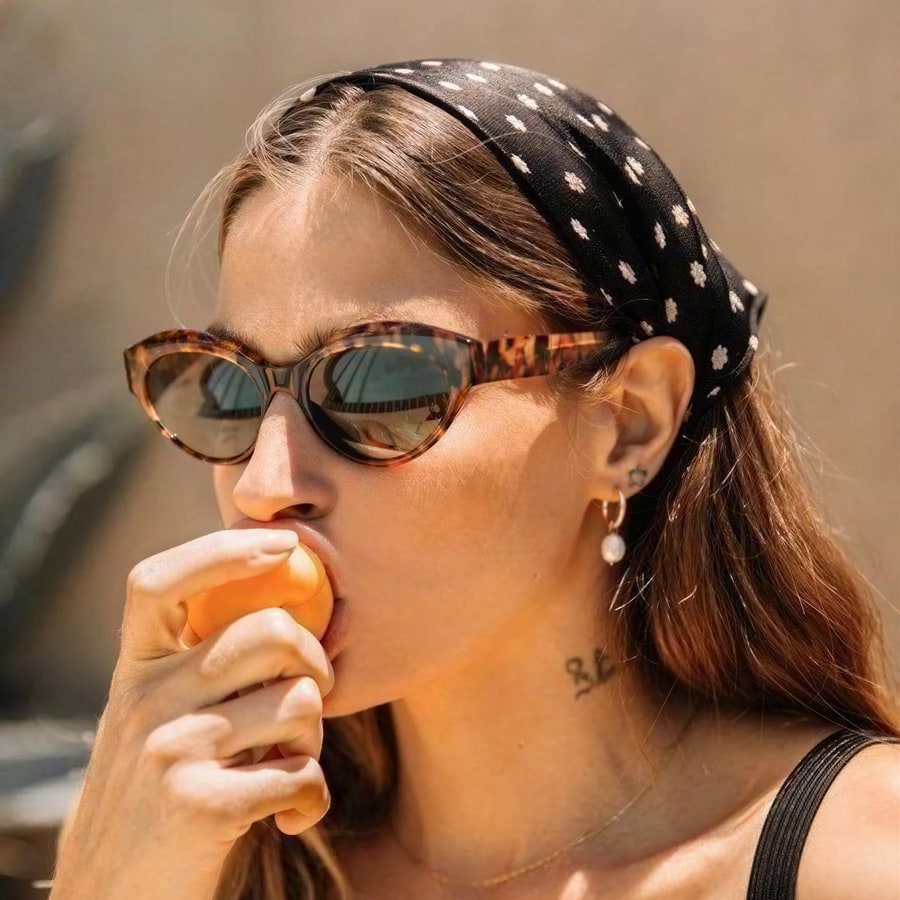 A one-to-one crop of the upscaled result: the reflection in her tortoiseshell sunglasses and the flecks in her headscarf hold up at full zoom
