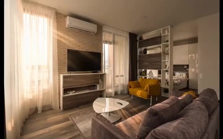The same listing in the golden-hour style: brick wall, TV unit, mustard armchair and grey sofa all unchanged, but lit by warm low sun with long shadows raking across the plank floor