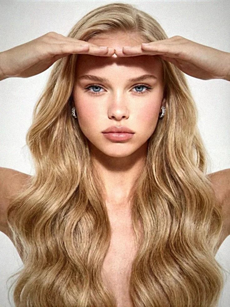 The same frame after the camera pass: fine sensor grain across skin, hair and backdrop, warmer tone and softer highlights, so the shot reads as photographed rather than generated