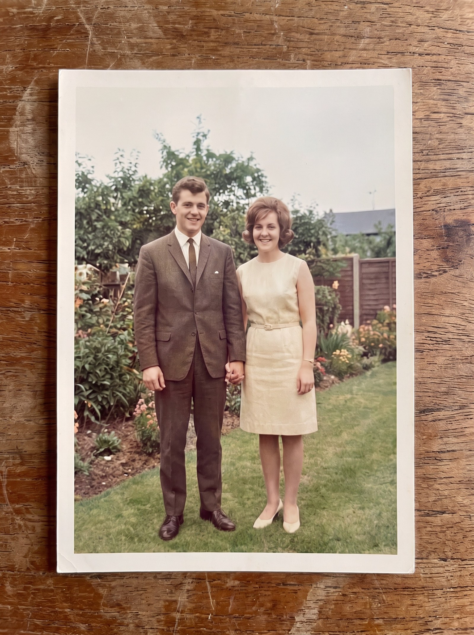 The same photograph after restoration: creases, tears and staining gone, colour and fine detail recovered, the couple and garden unchanged